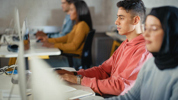 istock Handsome Smart Male Student, Studying in University with Diverse Multiethnic Classmates. He Works on Desktop Computer in College. Applying His Knowledge to Acquire Academic Skills in Class. 1363276512