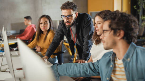 istock Lecturer Helps Scholar with Project, Advising on Their Work. Teacher Giving Lesson to Diverse Multiethnic Group of Female and Male Students in College Room, Teaching New Academic Skills on a Computer. 1363276552