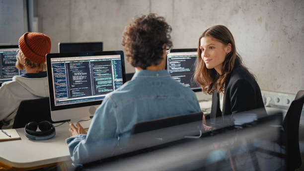 jeunes étudiants intelligents qui étudient à l’université avec divers camarades de classe multiethniques. les chercheurs collaborent dans la salle de l’université sur un projet informatique, écrivant du code logiciel dans un travail d’équipe r - web designer photos et images de collection