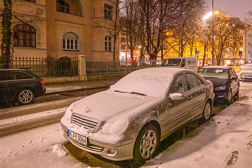 Snow covered cars in an early evening in the center of the German city Munich which is the capital city in Bavaria