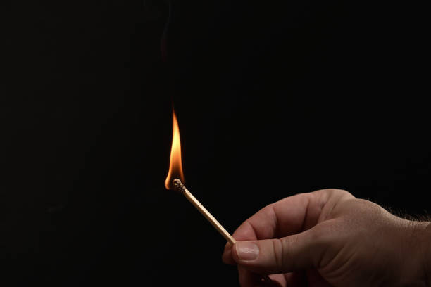 istock Hand holding burning match stick on black background 1363282750
