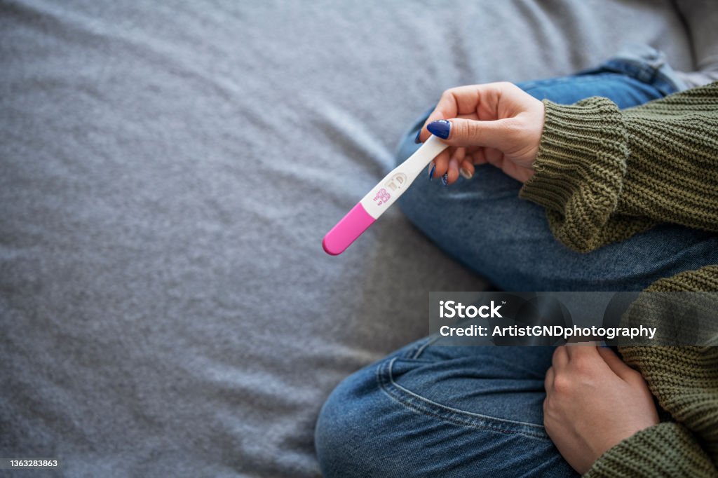 Woman holding positive pregnancy test. Unrecognisable woman holding positive pregnancy test. Pregnancy Test Stock Photo