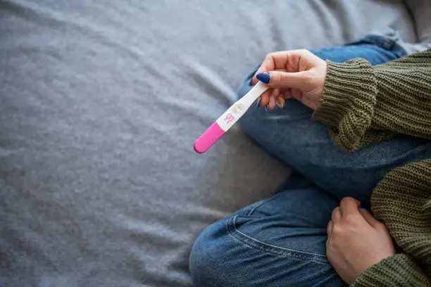 Photo of Woman holding positive pregnancy test.