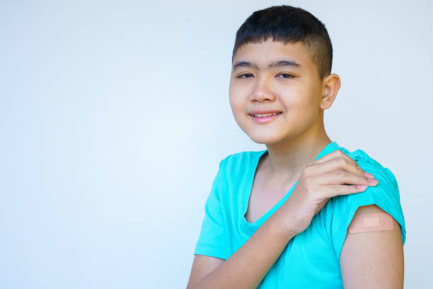 istock Portrait rural Asian boy standing against white background looking camera smiling happily after vaccinating against coronavirus in preparation for school term., Concept of the boy after vaccination 1363284008