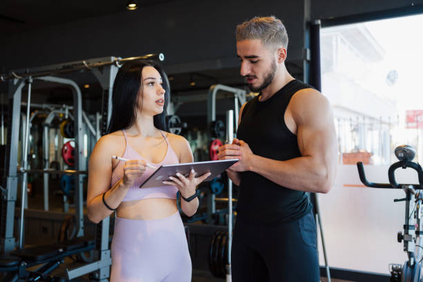 istock Personal Trainer Working With Young Male Client At Gym 1363285143