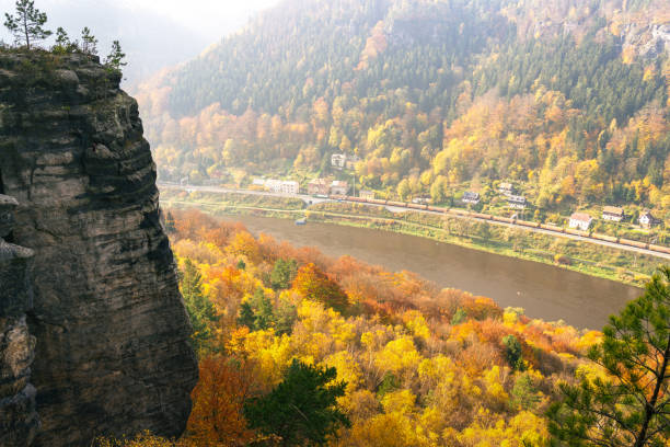 pociąg towarowy jadący przez kanion rzeki łaby w górach piaskowcowych łaby, republika czeska. piękny wąwóz otoczony formacjami skalnymi z piaskowca jesienią. kolorowe jesienne drzewa w słoneczny dzień - elbe valley zdjęcia i obrazy z banku zdjęć
