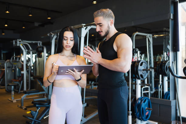 istock Personal Trainer Working With Young Male Client At Gym 1363286838