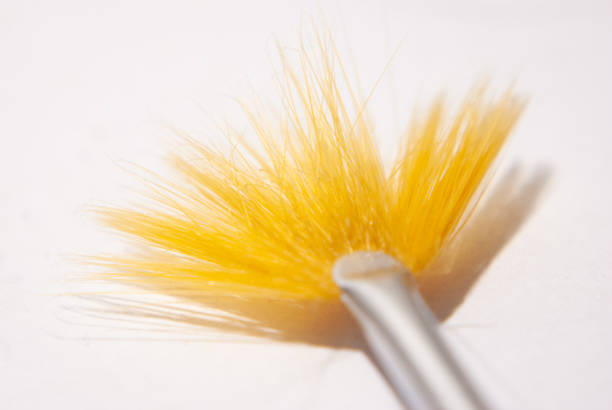 Close-up macro shot of a paintbrush with red paint on its bristles resting on a textured white surface
