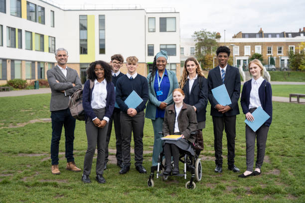 Secondary students and teachers in organized group portrait Full length front view of teenagers in uniform and mature teachers, all part of an inclusive secondary school environment, smiling at camera. organised group photo stock pictures, royalty-free photos & images