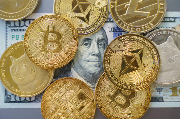 primer plano de bitcoin y monedas alternativas de criptomoneda de pie sobre un billete de cien dólares. vista de ángulo alto, sin personas - criptomoneda fotografías e imágenes de stock