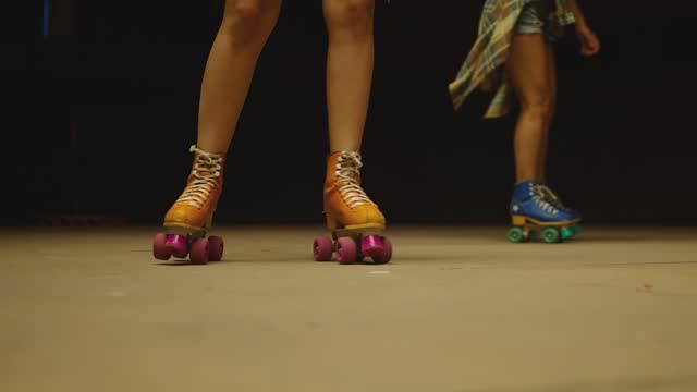 Female legs in roller blades, skating fast at the roller park on floor . Close-up legs of young women is professionally skating . Different kind of and colorful vintage  roller blades . Slow Motion