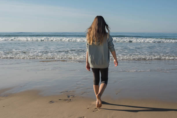 istock Beautiful girl walking barefoot on an ocean beach 1363294855