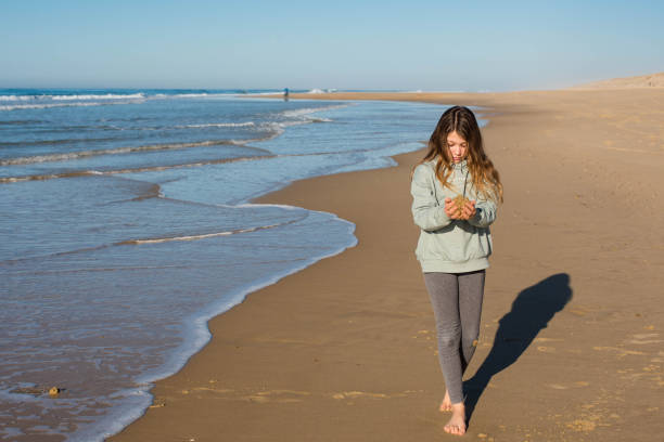 istock Beautiful girl walking barefoot on an ocean beach 1363295603