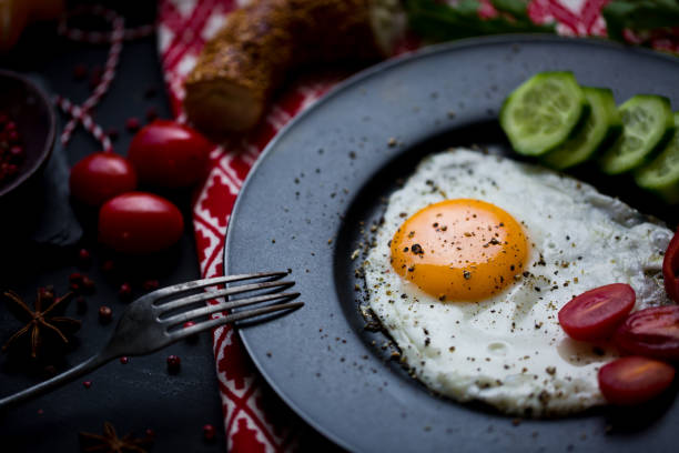 istock Breakfast set for christmas. Pan of fried eggs. Cucumber and cherry-tomatoes with Turkish bagels on dark table surface, top view. Christmas Breakfast. 1363300633