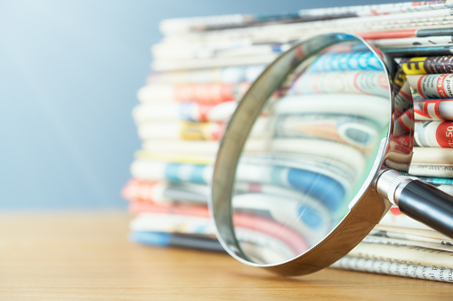 Stack of newspapers and magnifying glass