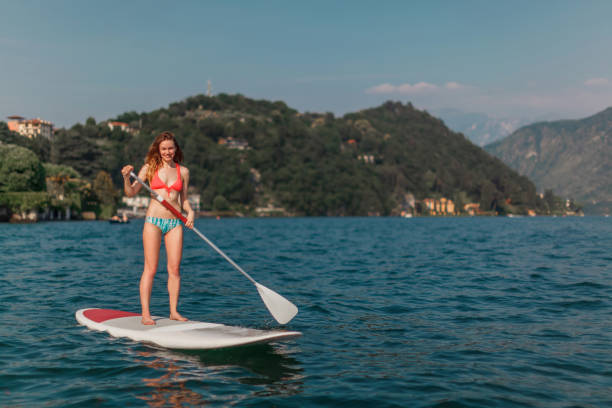 woman paddle boarding on the mountain lake - women paddleboard bikini surfing imagens e fotografias de stock