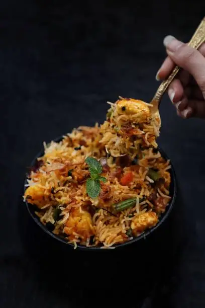 Veg biryani with cottage cheese and beans and vegetables on black background.Food photography and food styling. Hand
