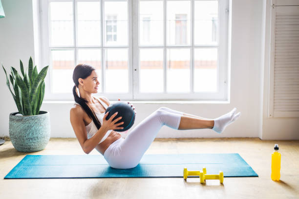 Sportive woman training at home Ahtletic beautiful woman training at home - Young girl doing fitness in her apartment, concepts about fitness, sport and health fitness ball photos stock pictures, royalty-free photos & images