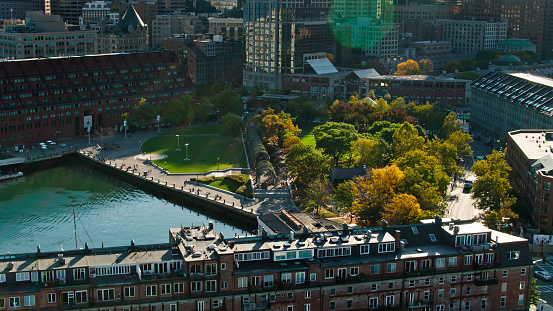 Aerial shot of Boston, Massachusetts on a clear day in Fall, looking down on Christopher Columbus Waterfront Park in the North End. \n\nAuthorization was obtained from the FAA for this operation in restricted airspace.
