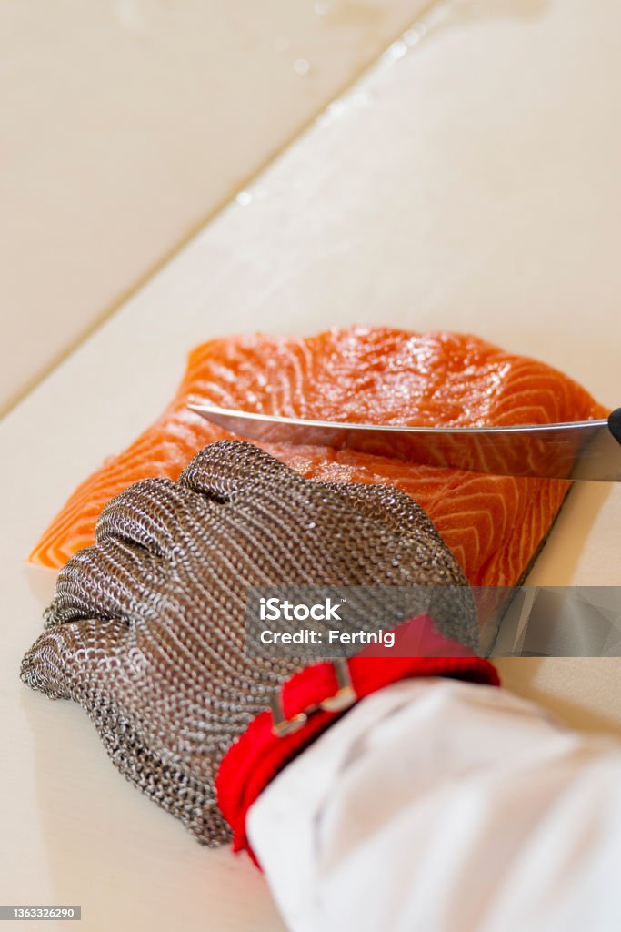 A professional cutting fish A close-up of an employee cutting salmon in a commercial kitchen or food processing plant. Cutting Stock Photo