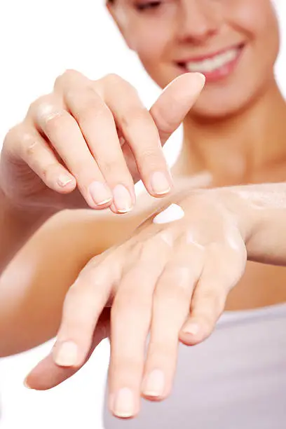 Image of female hands being treated with handcream on white background