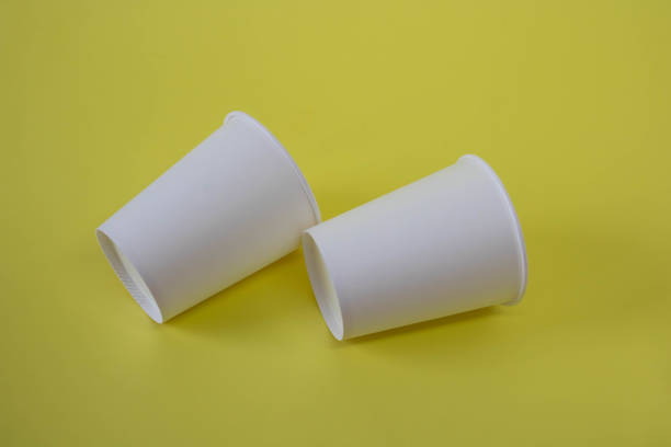 istock Two white paper cups on a yellow background 1363331129