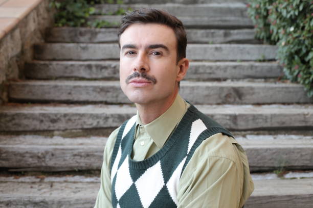 man with a mustache wearing sleeveless rhombus sweater - clothes iron 1970s imagens e fotografias de stock