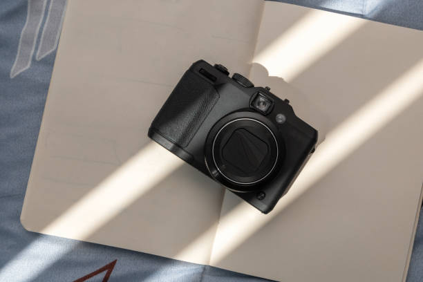istock modern camera on an open notebook with blank sheets, details of technology and articles of art, hobbies 1363336207