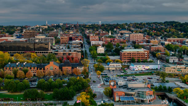 Aerial View from Lakeshore Looking Along Streets in Burlington, Vermont Aerial shot of Burlington, Vermont on a hazy evening in early Fall, looking along streets of historic buildings, shaded by trees that are beginning to to turn red, yellow and orange. The Green Mountains can be seen in the distance.
Authorization was obtained from the FAA for this operation in restricted airspace. burlington vermont shoreline stock pictures, royalty-free photos & images