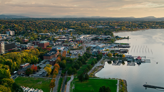 Drone shot of the shore of Lake Champlain in Burlington, Vermont at sunset, including the ferry terminal, commercial docks, and downtown streets shaded by trees that are beginning to to turn red, yellow and orange. The Green Mountains can be seen in the distance. 

Authorization was obtained from the FAA for this operation in restricted airspace.