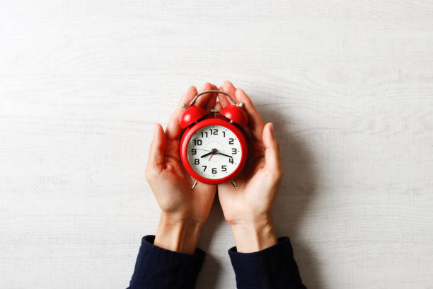 istock Person holding a red alarm clock with both hands 1363351844