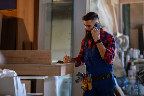 istock Young male carpenter working in workshop and using smartphone 1363352718
