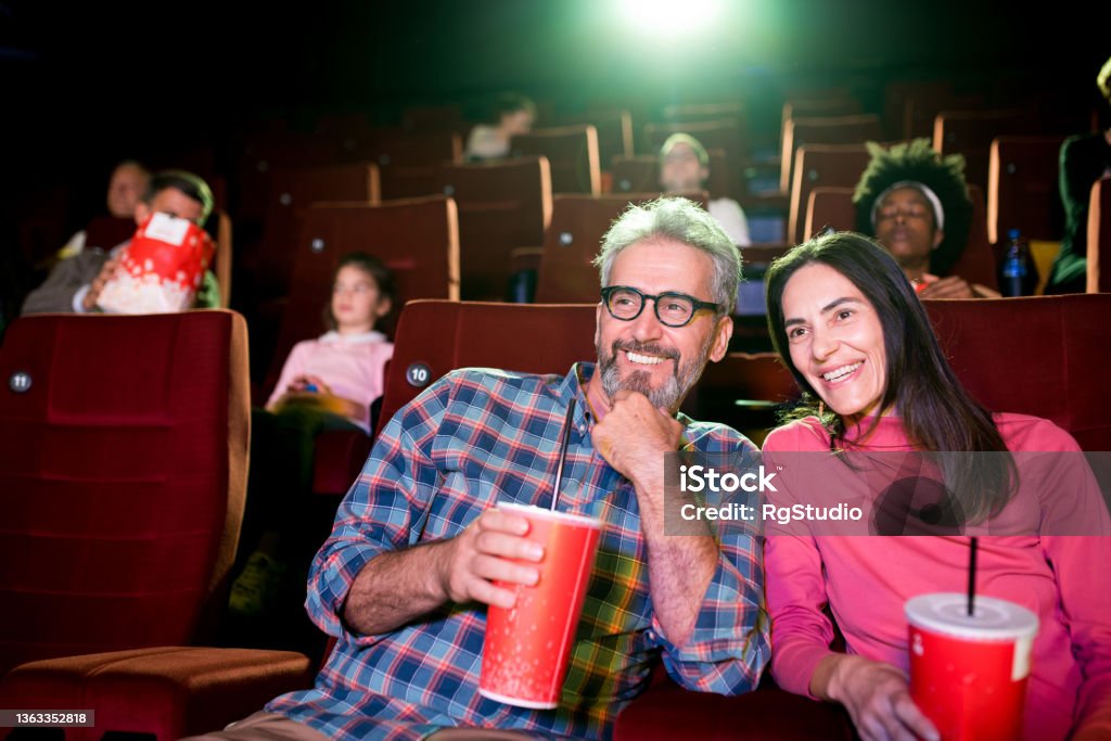 Man and woman enjoying watching a movie at the cinema Couple watching the movie at the cinema and enjoying. Dating Stock Photo