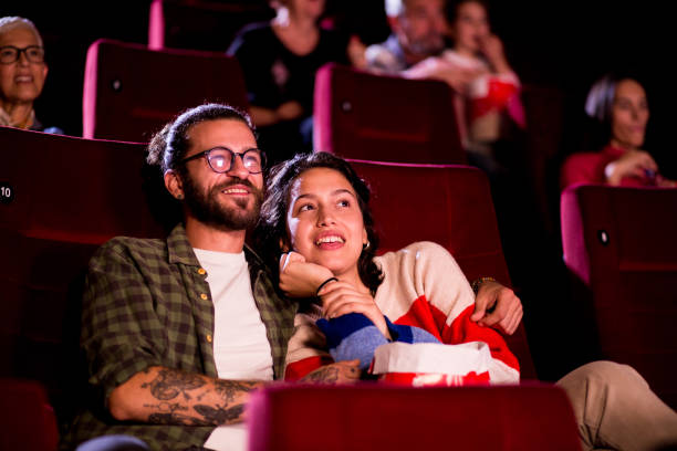 ritratto di una giovane coppia che si diverte mentre guarda una commedia romantica al cinema - attività romantica foto e immagini stock