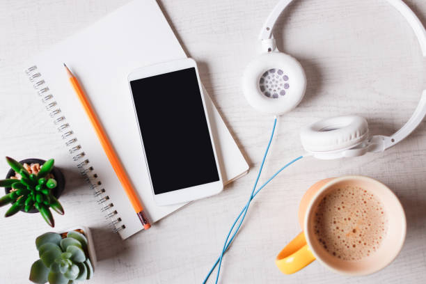 Overhead view of smartphone and accessories while drinking coffee