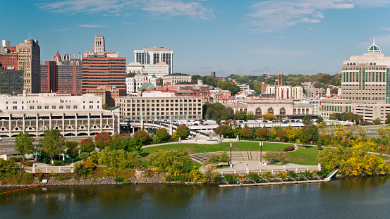 Aerial view over the Hudson River in Albany, New York, looking over Corning Preserve towards the downtown buildings. Light traffic is passing by on Interstate 787.