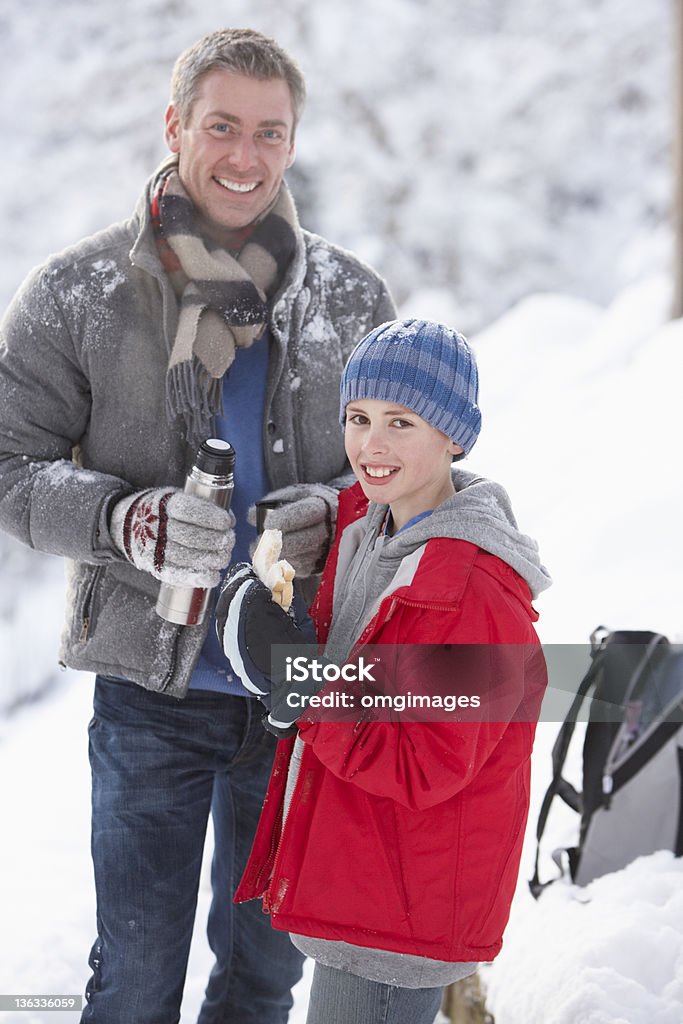 Отец и сын прекращения чтобы перекусить во время ходьбы - Стоковые фото Зима роялти-фри