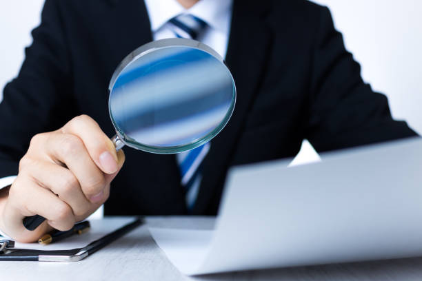 istock Businessman in a suit reading materials with a loupe 1363362129