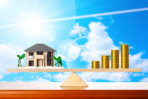 House and money seesaw balance blue sky background
