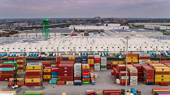 Aerial shot of the Port of Baltimore, Maryland, looking over an intermodal shipping container yard towards a huge fulfillment center.