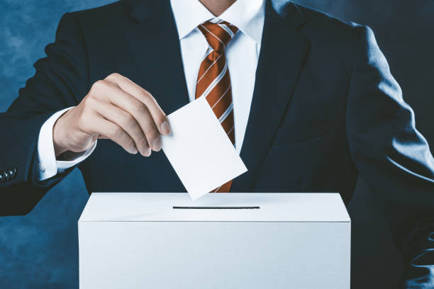 istock Dark background with businessman in red tie and voting 1363365183