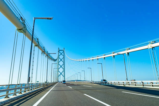 blauer himmel und akashi kaikyo autobahn - kobe bridge japan suspension bridge stock-fotos und bilder