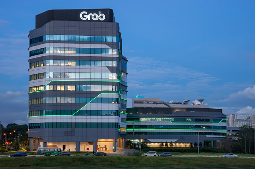 Singapore, Singapore - January 3, 2022: Vehicles parked on a street before Grab's headquarters at the One-North precinct. NASDAQ-listed Grab is the developer of a 'superapp' that provides transportation, food delivery and digital payment services in various Southeast Asian markets.