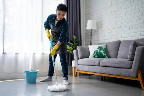 apuesto hombre asiático con delantal limpiando el piso en casa. chico lavando piso con palo de fregado y cubo en la sala de estar. - one floor fotografías e imágenes de stock