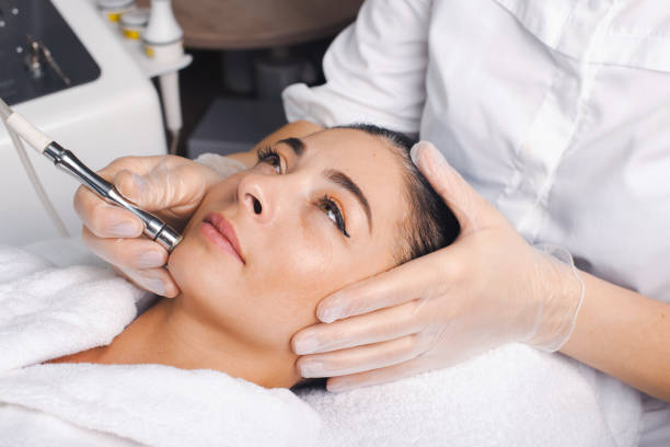 Close-up portrait of woman getting facial hydro microdermabrasion peeling treatment at cosmetic beauty spa clinic. Medical treatment. Rejuvenation treatment. Close-up portrait of woman getting facial hydro microdermabrasion peeling treatment at cosmetic beauty spa clinic. Medical treatment. Rejuvenation treatment. microdermabrasion stock pictures, royalty-free photos & images