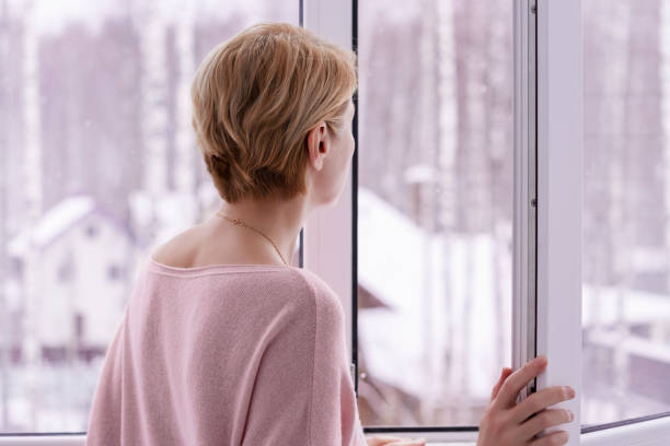 istock A woman looking out the window in winter 1363383278