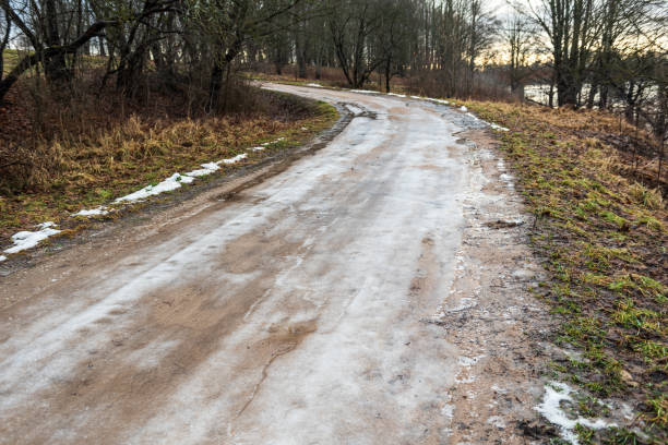 Melting ice on a country road in winter day.