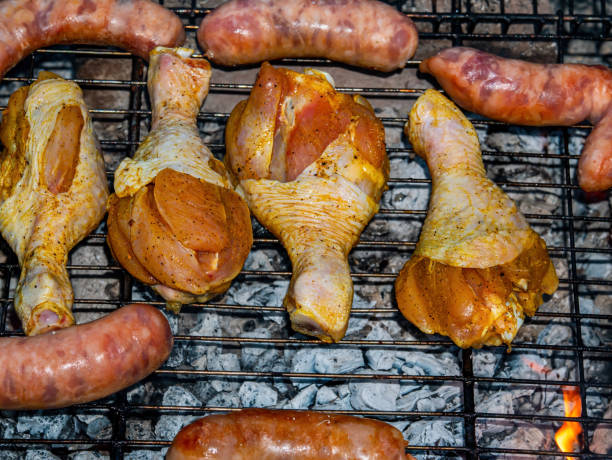 istock Chicken legs and meat sausages on an iron grill mesh. 1363403533