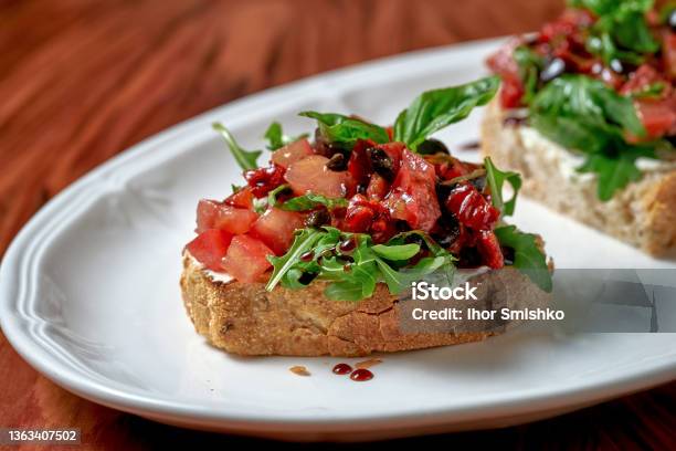 Bruschetta With Sundried Tomatoes And Feta In A White Plate On A Wooden Background Stock Photo - Download Image Now