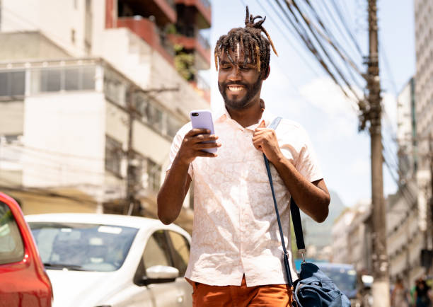 Stylish young man using his phone while walking down the street